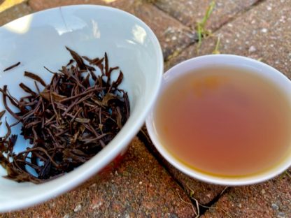 I close off of lapsang Souchon, Chinese black tea in a cup and used leaves in a bowl on bricks outside