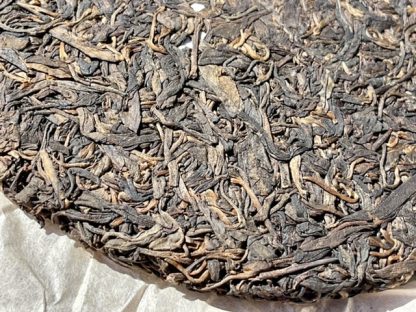 Close up of an aged raw puerh tea cake opened wrapper in the sun