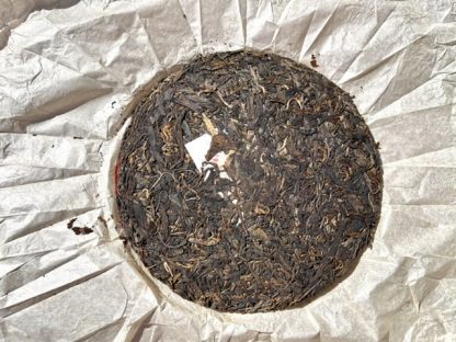 The front of an open wrapper aged raw puerh tea cake