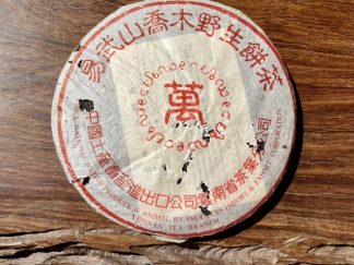 an aged raw puerh tea cake innits wrapper on a table