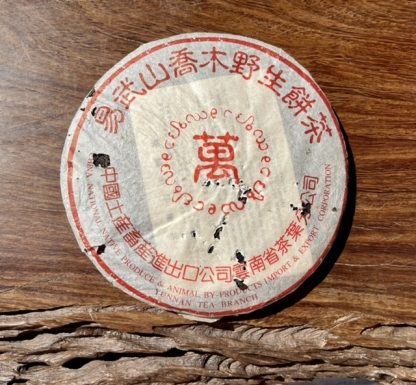 an aged raw puerh tea cake innits wrapper on a table