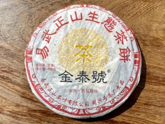 The front of an aged raw puer tea cake with wrapper on a table