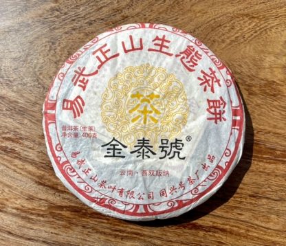 The front of an aged raw puer tea cake with wrapper on a table