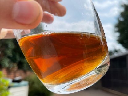 Man holding a glass of Chinese rougui Yancha oolong tea to the sky