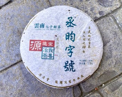 An unopened raw puerh tea cake on the driveway outside