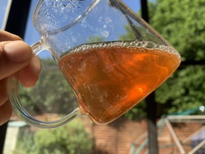 Yuan Yuan raw puerh tea in a glass holding to the sky