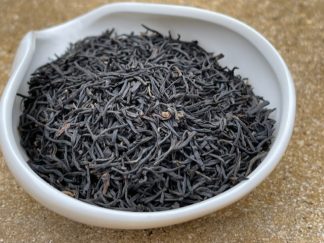 Close-up of lapsang, Souchon, black tea leaves in a bowl on a brick